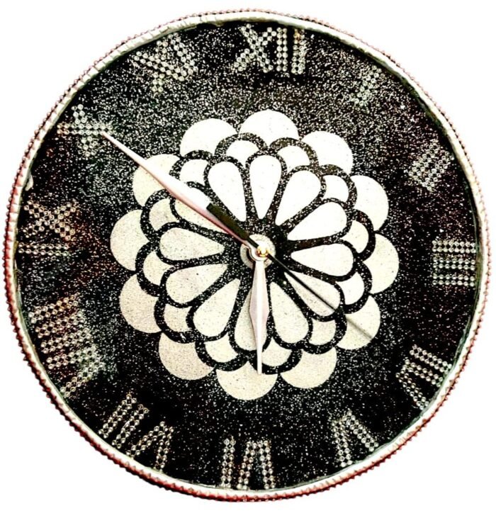 kolam Artistic Design & Craftsmanship Kolam-Inspired Mandala Pattern: The heart of this clock features a sacred geometric floral motif, symbolizing balance, unity, and positive energy. Luxury Black & White Contrast: The bold jet-black resin base paired with shimmering white mandala details creates a striking, high-end look. Crystal Studded Roman Numerals: Each numeral is designed with embedded shimmering stones, offering sparkle and a regal touch. Intricate Resin Detailing: Hand-poured resin with precision artistry ensures a smooth glossy finish that enhances the luxurious aesthetic.